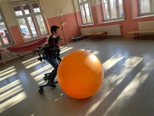 Schüler im Lauftrainer rollt einen Gymnastikball vor sich her