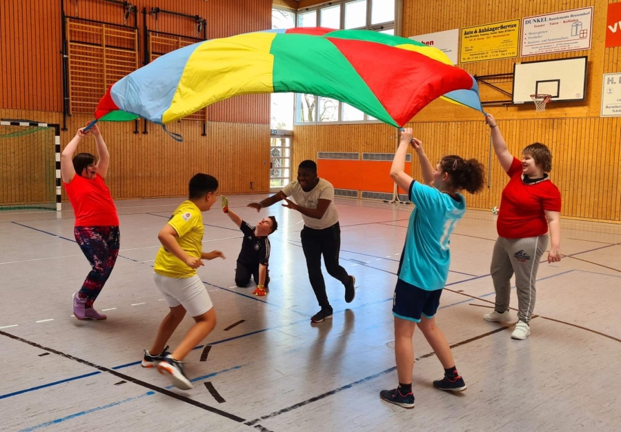 Schüler in der Turnhalle mit Schwungtuch