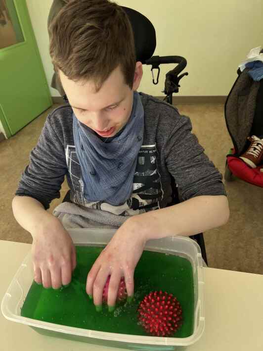 Schüler holt Igelbälle aus einer Schale mit grüner Flüssigkeit