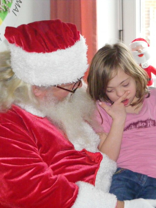 Schülerin sitzt beim Weihnachtsmann auf dem Schoß