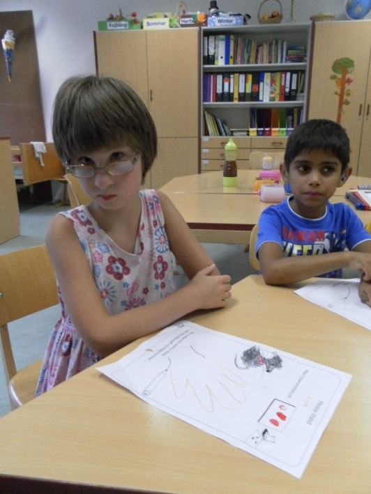 Schüler zeichnen Hand auf einem Arbeitsblatt mit Stiften nach