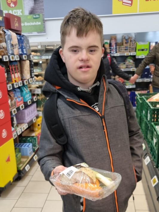 Schüler im Supermarkt mit Suppengrün in der Hand