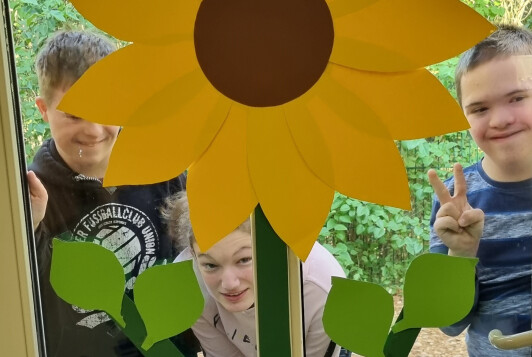 Schüler stehen hinter einem Fenster, welches mit Sonnenblumen aus Papier beklebt ist